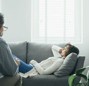 Sad woman lying on sofa in therapy room